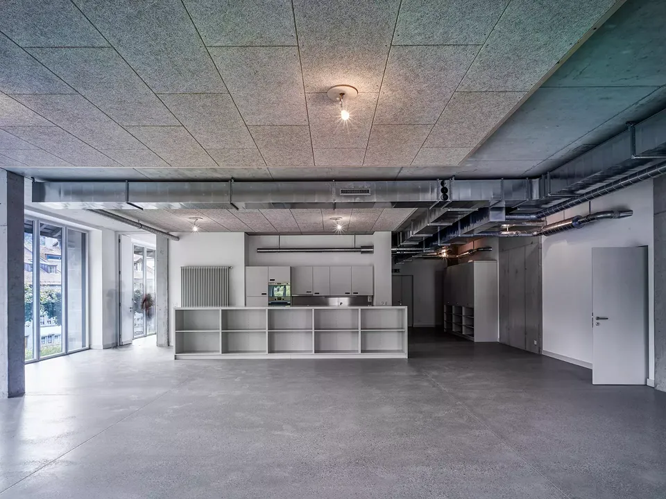 Le premier étage est occupé par la maison de quartier.  Pour les besoins, la salle communautaire est agencée avec du mobilier sur mesure fabriqué en mdf. Au sol, la chape est en béton poncé.