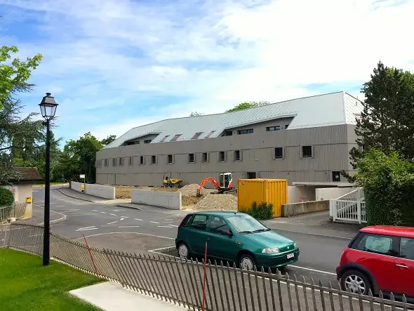 Ansicht Westfassade gegen chemin du Vieux-Four / Fassade aus sägerohem Lärchenholz, Dach aus Zink, Dachterrasse