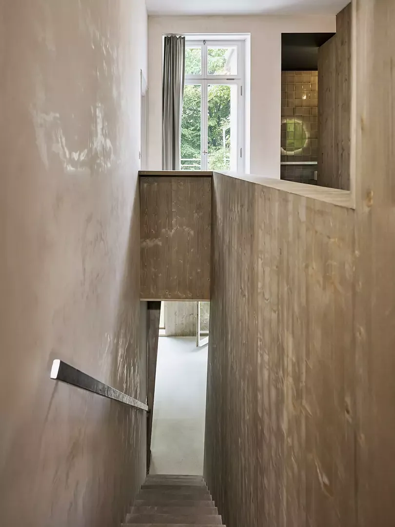 Vue du 1er étage sur l’escalier étroit, à droite,  l’habillage en bois, recouvert d’un glacis vert olive.