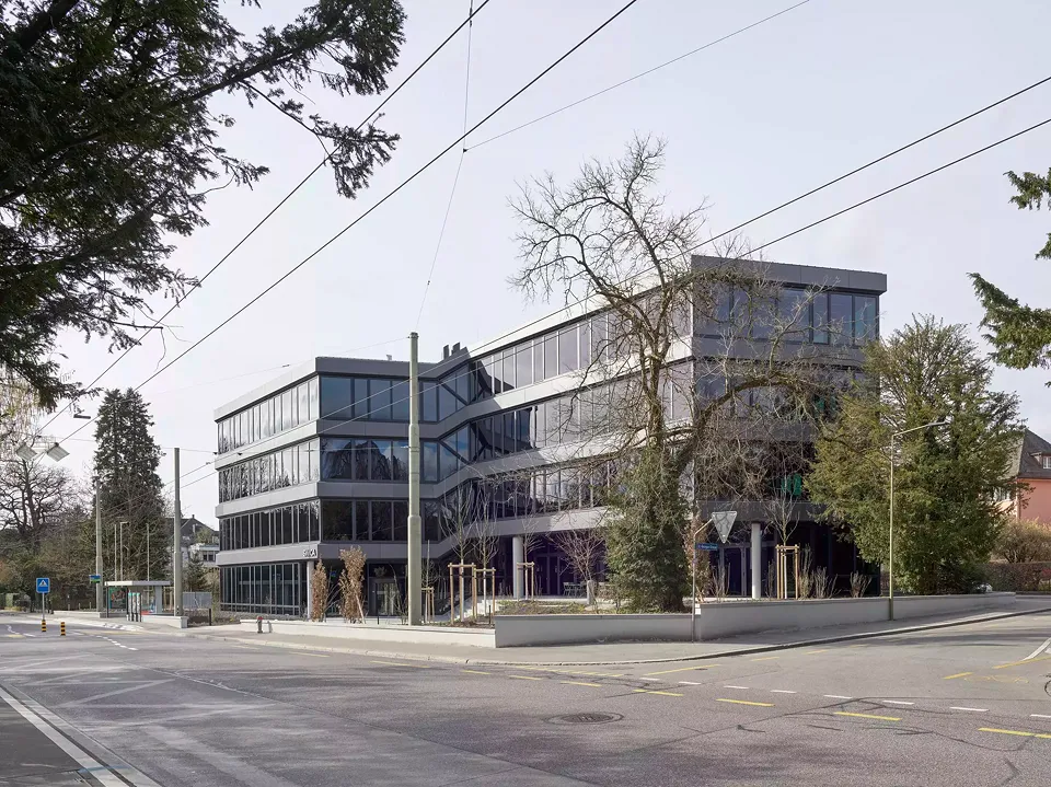 Blick von der Römerstrasse stadteinwärts Richtung Haupteingang. Die Fassade ist in Segmente aufgeteilt, deren einzelne Längen quartiertypisch sind.