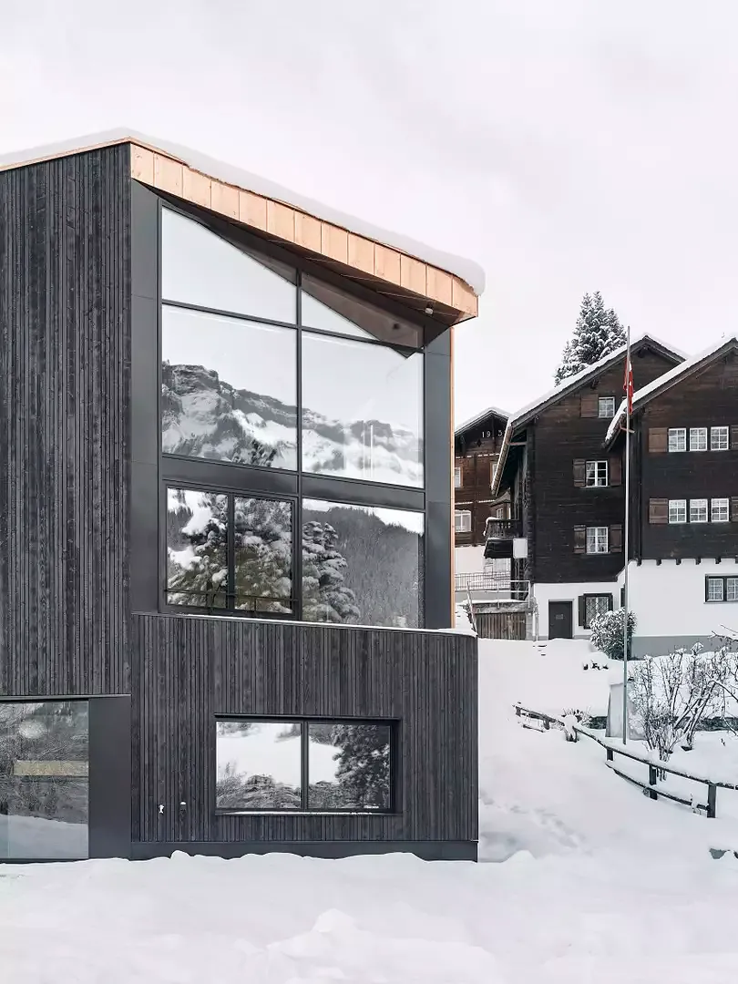 Das rauhe verkohlte Holz de Fassade bildet einen starken Kontrast zu den flächigen strukturellen Öffnungen.