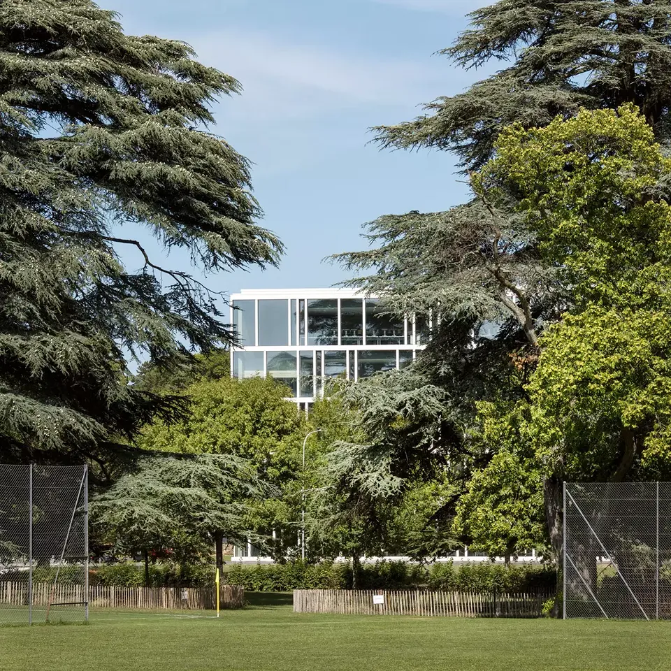 La délicate structure de  la façade du bâtiment  scolaire contraste avec le  vert des arbres séculaires  des anciens jardins.