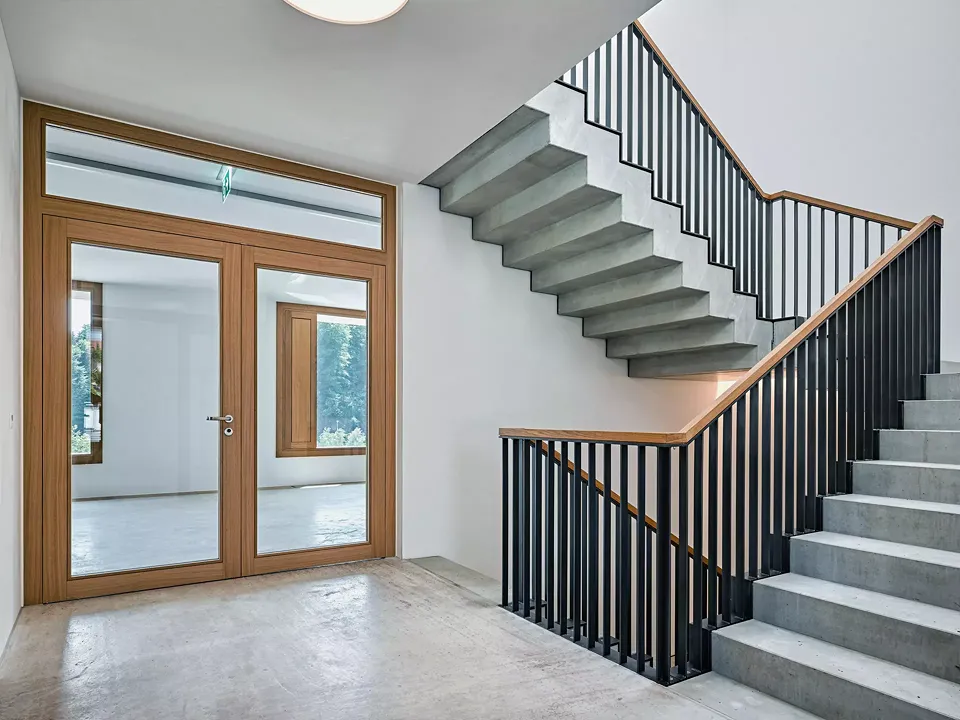 Escalier en béton brut avec un garde-corps en  acier et une main courante en bois de chêne.