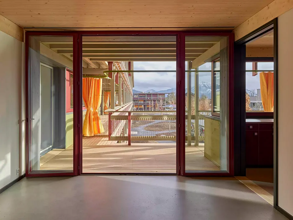Der Wohnraum lässt sich im Sommer auf die Veranda erweitern. Vorhänge bieten die Möglichkeit, Privatsphäre zu schaffen und bringen ein spielerisches Element in die gegliederte Holzfassade.