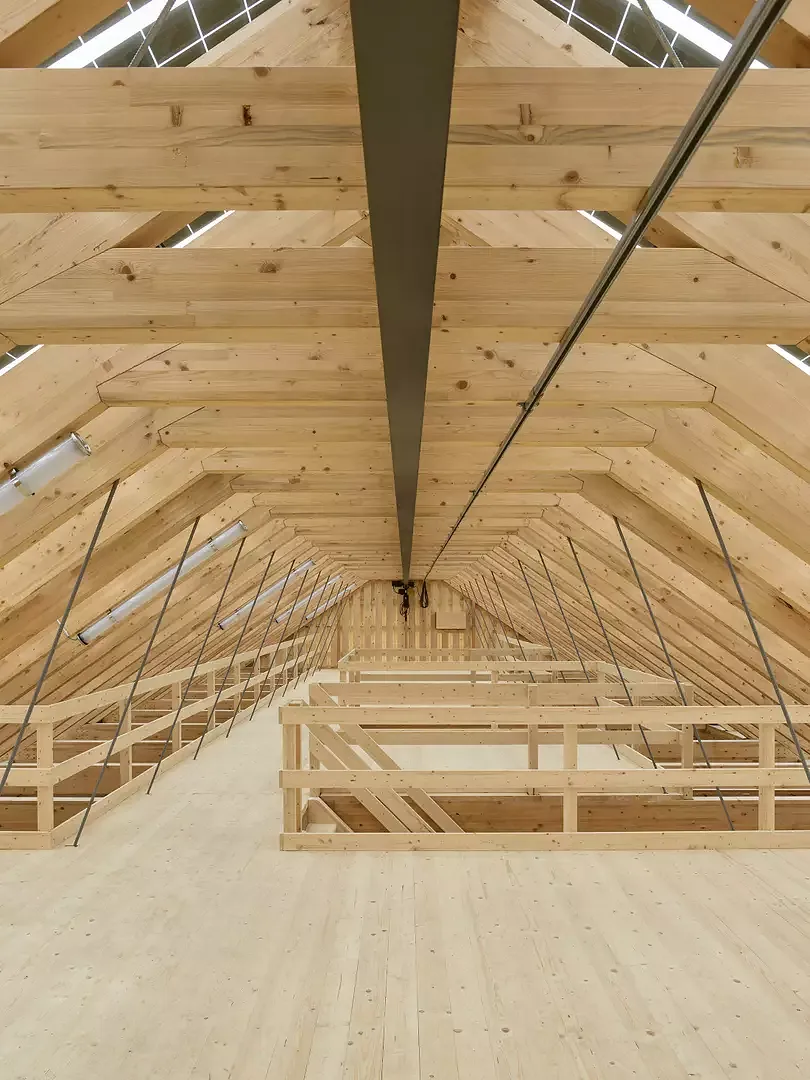 Das feingliedrige Sparrendach bietet auf einer Galerie über der Einstellhalle Lagerfläche, die mit einer Kranbahn beschickt wird.