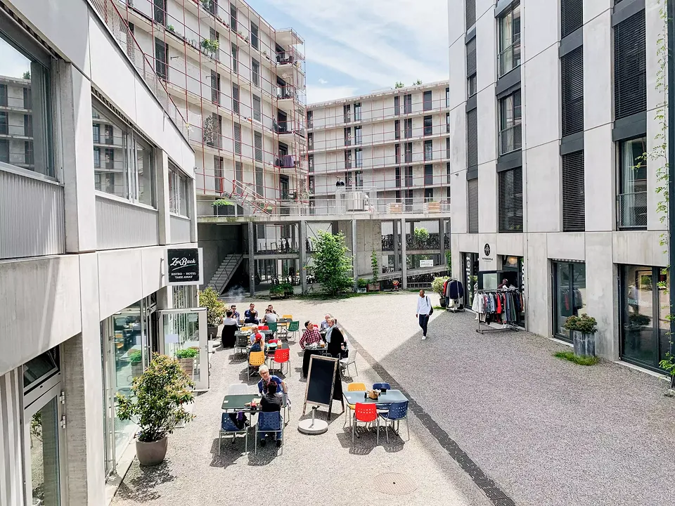 Prendre un café dans une petite ruelle,  cela crée une sensation d’urbanité. Et  c’est bien ce dont peuvent profiter les clients l’hôtel Zwiback, les résidents de  la coopérative ainsi que les employés des nombreuses entreprises commerciales.