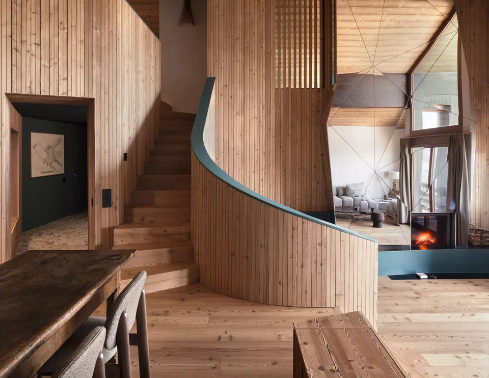 Die renovierte Maisonettewohnung in Anzère verbindet offene Räume und versetzte Ebenen mit einer Materialität aus Lärchenholz und Lehmputz.