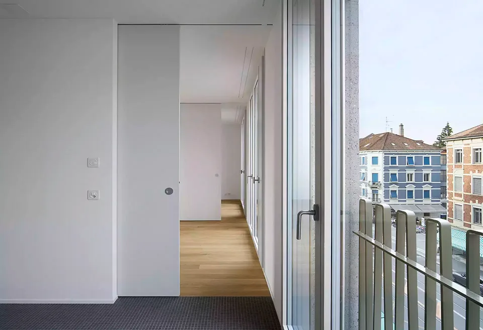 Vue de la cuisine sur les deux autres espaces en enfilade. Des fenêtres à la française à hauteur de plafond donnent sur la Klybeckstrasse, une rue très fréquentée.