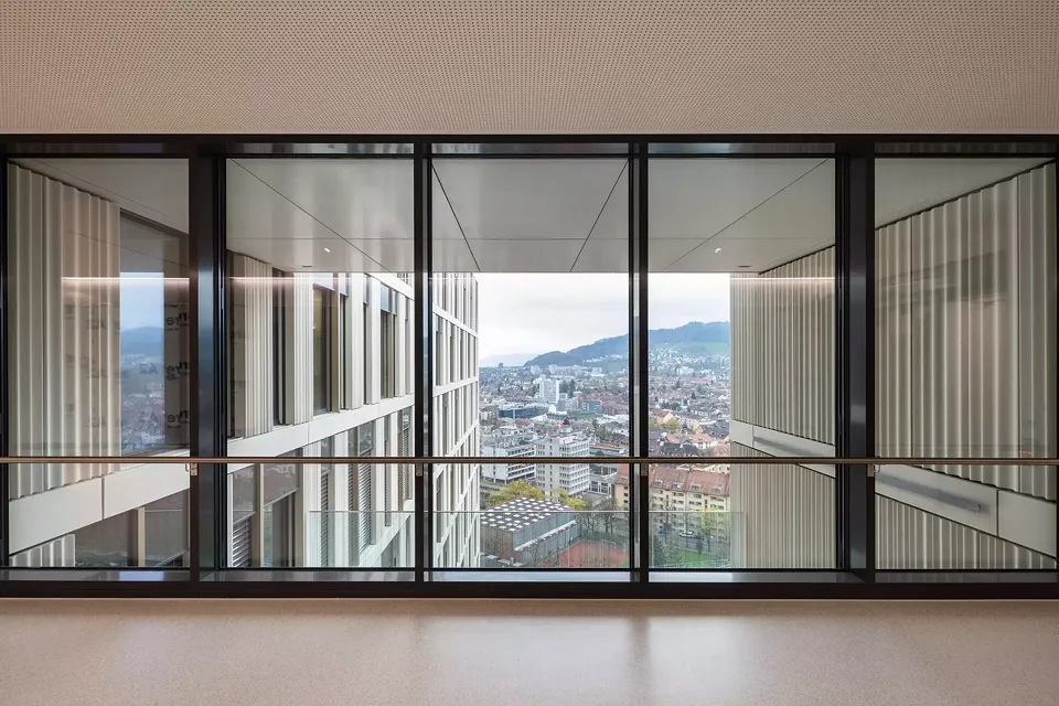 Blick aus dem Vorbereich der Aufzüge in Geschoss P nach Süden. Raumhohe Fensterflächen in den hoch frequentierten Verkehrsflächen sorgen für natürliche Beleuchtung und eine Orientierung durch Sichtbezüge zum urbanen Umfeld.