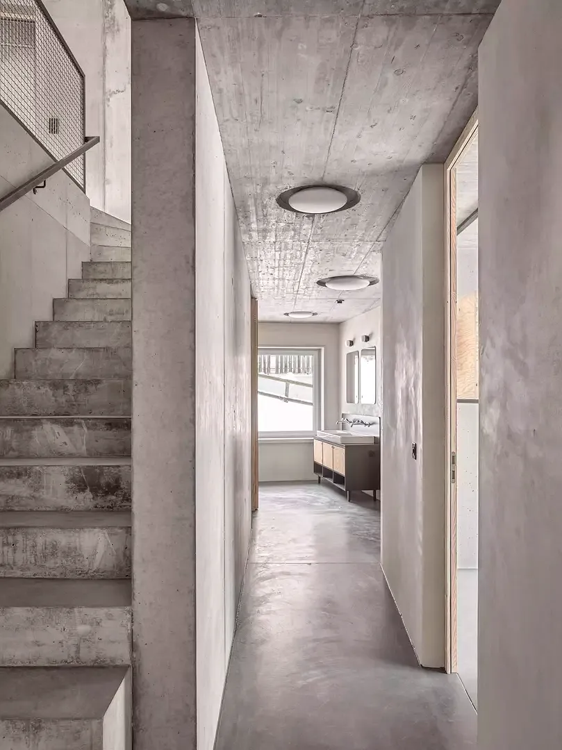 Eine über alle drei Geschosse führende Betonwand gliedert den Grundriss in eine zum Hang und eine zum Tal orientierte Seite.
