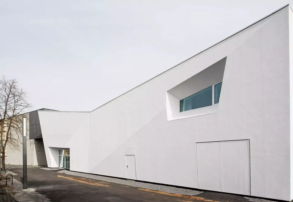 Vue sud-ouest avec une  brisure diagonale prononcée: Le lettrage ne brille que très légèrement, si bien qu’il est à peine reconnaissable, comme  par exemple ici à gauche  de la fenêtre ou au-dessus  de l’entrée principale.