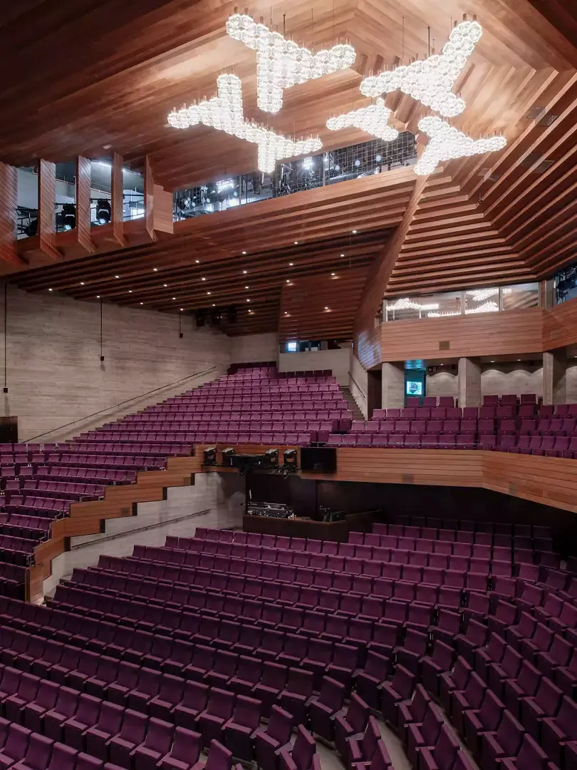 La salle ressemble à  une grotte introvertie  où la couleur violette  du revêtement des  sièges contraste avec  celle du béton et le  Redwood plus sombre.