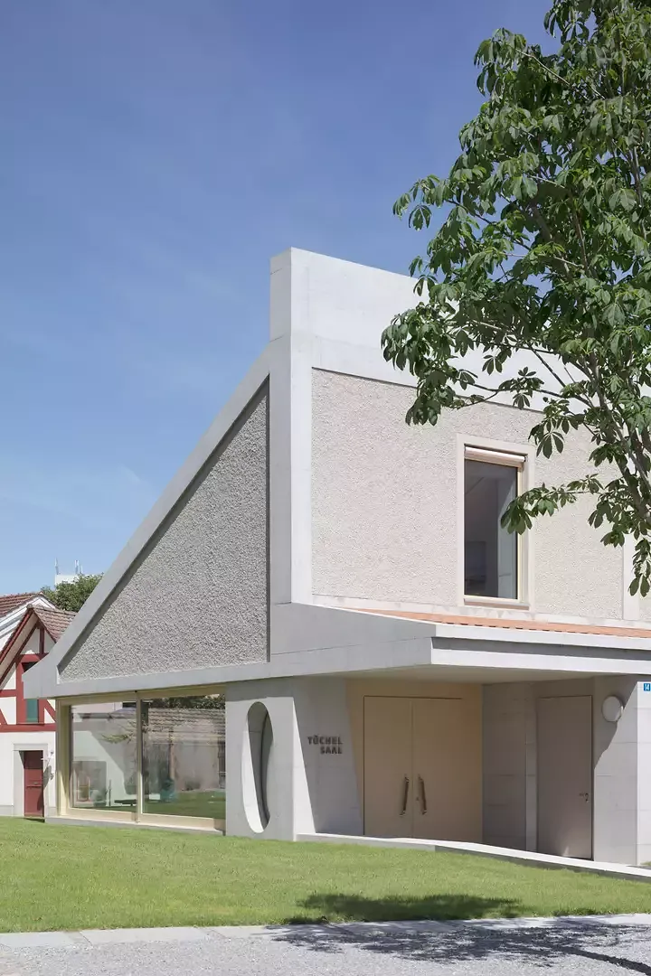Les architectes ont utilisé la pente du terrain afin de créer un espace d’entrée enfoncé de quelques centimètres. L’avant-toit donne l’impression d’être  déjà entré dans le bâtiment avant  d’avoir passé la porte.