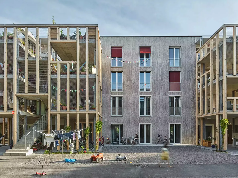 Dreigeschossige Leichtkonstruktionen erschliessen die einzelnen Gebäude und markieren die Adresse, strukturieren die Gasse und schaffen Nischen im Aussenraum