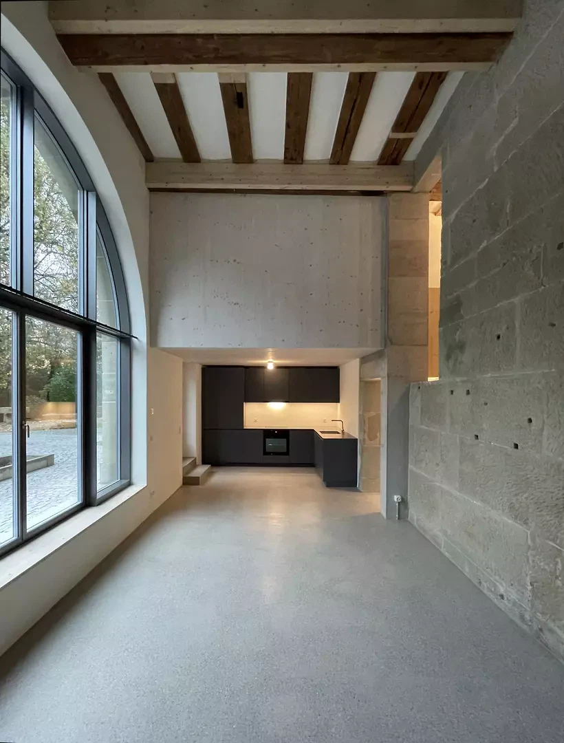 Hinter der Rundbogenöffnung in der Westfassade  befindet sich ein lichtdurchfluteter Wohnraum.