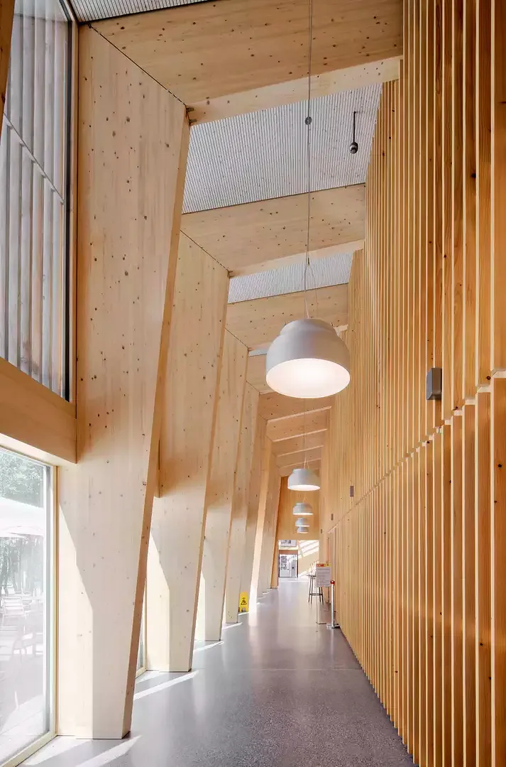 Couloir intérieur menant à  la grande salle à manger, au fond du foyer. À droite, la zone de libre-service, à gauche,  deux portes vitrées donnent  sur la terrasse extérieure.