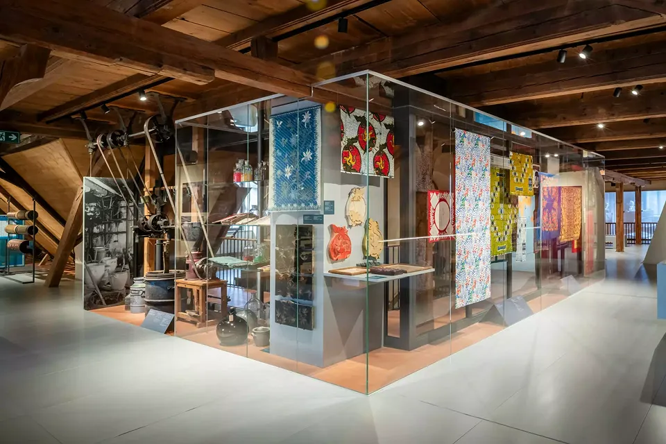 Grande vitrine visible des quatre côtés avec des objets de la Druckwerkstadt et des tissus et étoffes produits à Glaris.