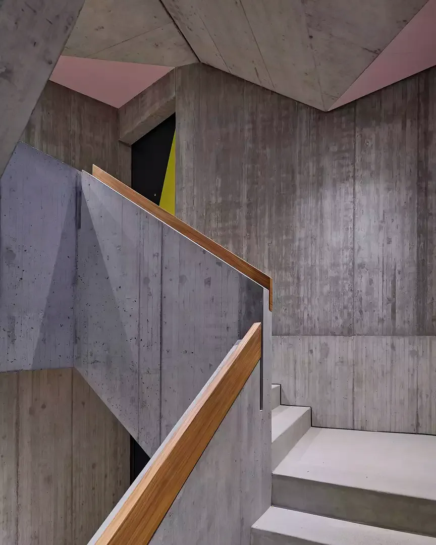 Das Treppenhaus aus Sichtbeton vermittelt mit einzelnen Farbakzenten zwischen dem öffentlichen und privaten Raum.