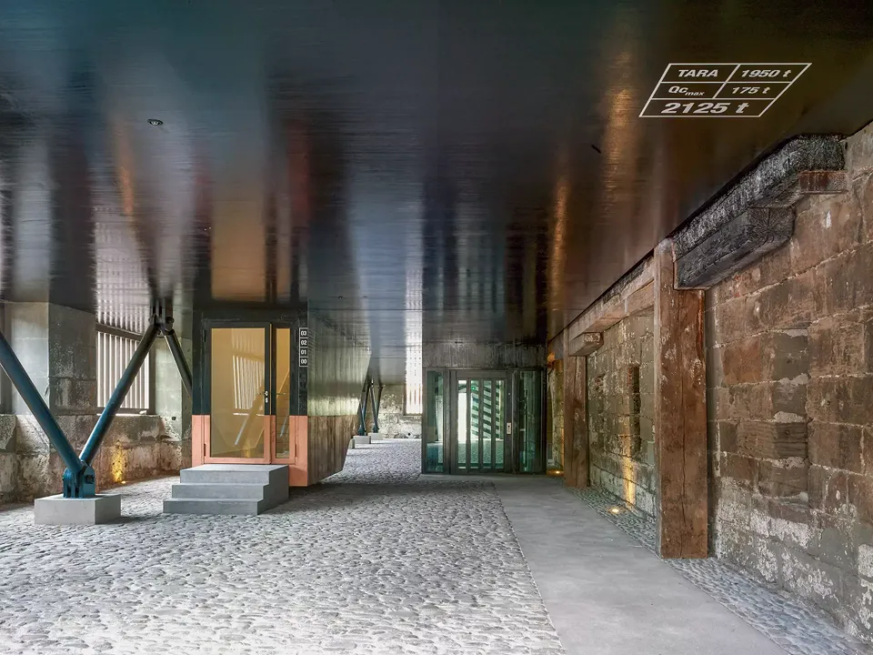 Der Zugang zum Gebäude  erfolgt durch eine kleine Holztür. Wie bei einem Frachtschiff,  wird dieser von einer Reihe von V-förmigen Stützen Metall getragen.