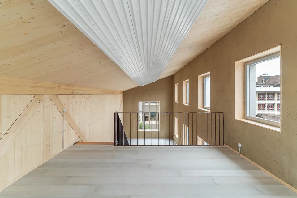 Intérieur avec vue sur les murs en crépi d'argile et l'escalier menant à la mezzanine