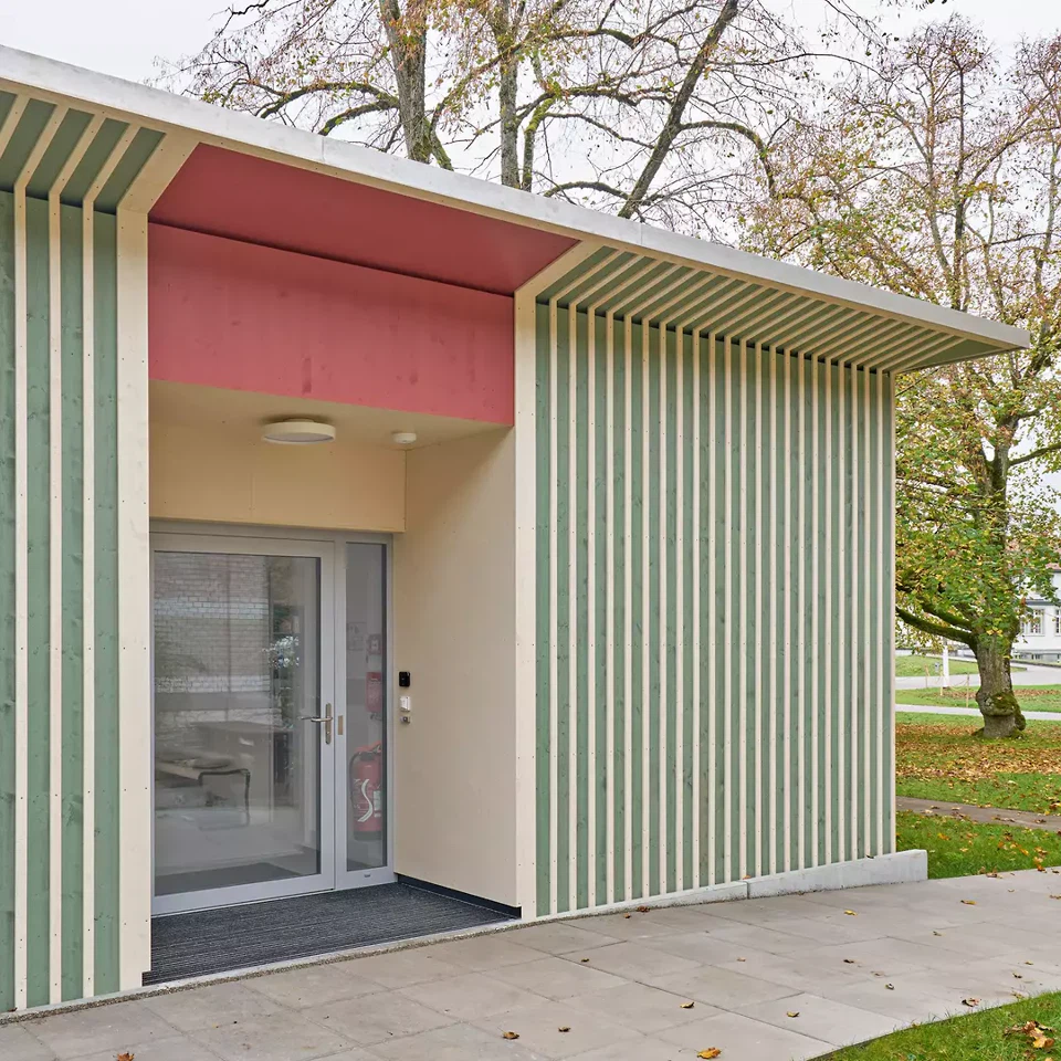 Der Eingang ist stirnseitig am höchsten Punkt deber Topografie angeordnet. So entstehen minimale Eingriffe in die Umgebung, während der stehende Verbindungsweg als Erschliessung zum Gebäude genutzt werden kann.