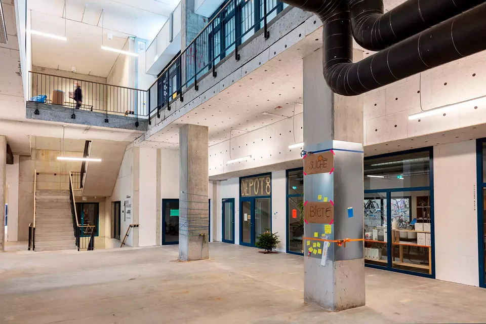 Le cœur de la coopérative est  ce que l’on appelle la «place du village», à la fois foyer et hall multifonctionnel, avec accès à un magasin ouvert 24 heures sur 24.