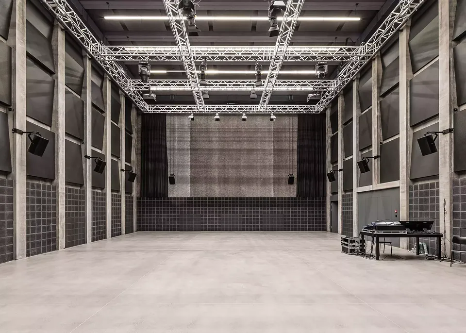La boîte noire «Kosmos»  est une construction  de type «maison dans  la maison». Des dalles acoustiques foncées  dans la zone inférieure  sont combinées avec  du béton nervuré dans  la zone supérieure.