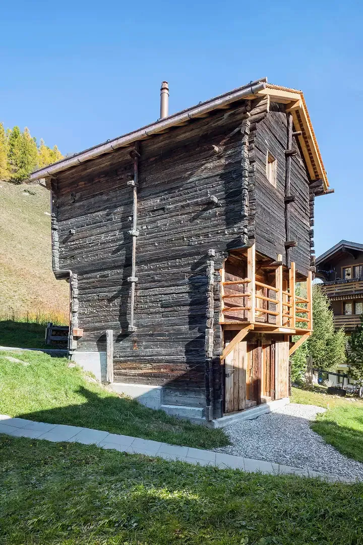 L’implantation dans la pente du séchoir est soulignée par le nouveau socle en béton. L’horizontalité des madriers met en valeur les saillies du volume qui rendent lisibles les trois niveaux du logement.