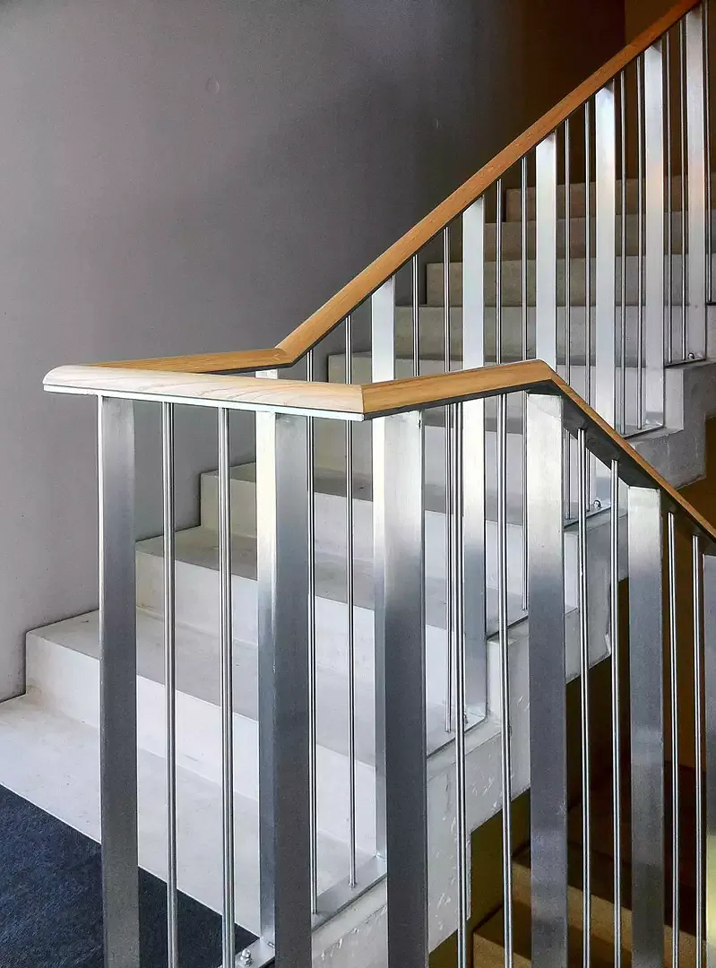 An den jeweilig äussersten Enden der beiden Gebäudeflügel befindet sich eine betont funktionale Innentreppe aus Aluminium, die sehr gekonnt mit einem Holzgeländer kombiniert wurde. Diese zwei Struktur elemente zeichnen sich durch ihr leichtes und elegant