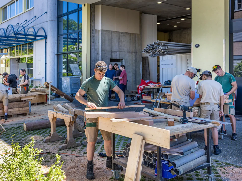 Gemeinsam mit Lernenden und Berufsbildnern aus den Holzbaubetrieben werden die Elemente der Strukturen vor den Ateliers Ebenau in Horw vorproduziert.