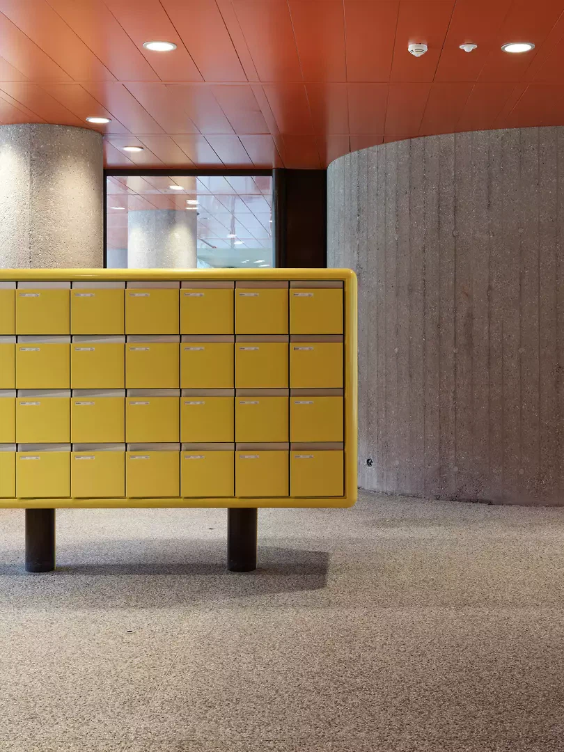 Dans le hall d’entrée, les couleurs caractéristiques ont été conservées ou restaurées. Un comptoir d’accueil et une partie du plafond ont pu être restaurés; les boîtes aux lettres ont été remplacées, et leur couleur s’inspire de celle d’origine.