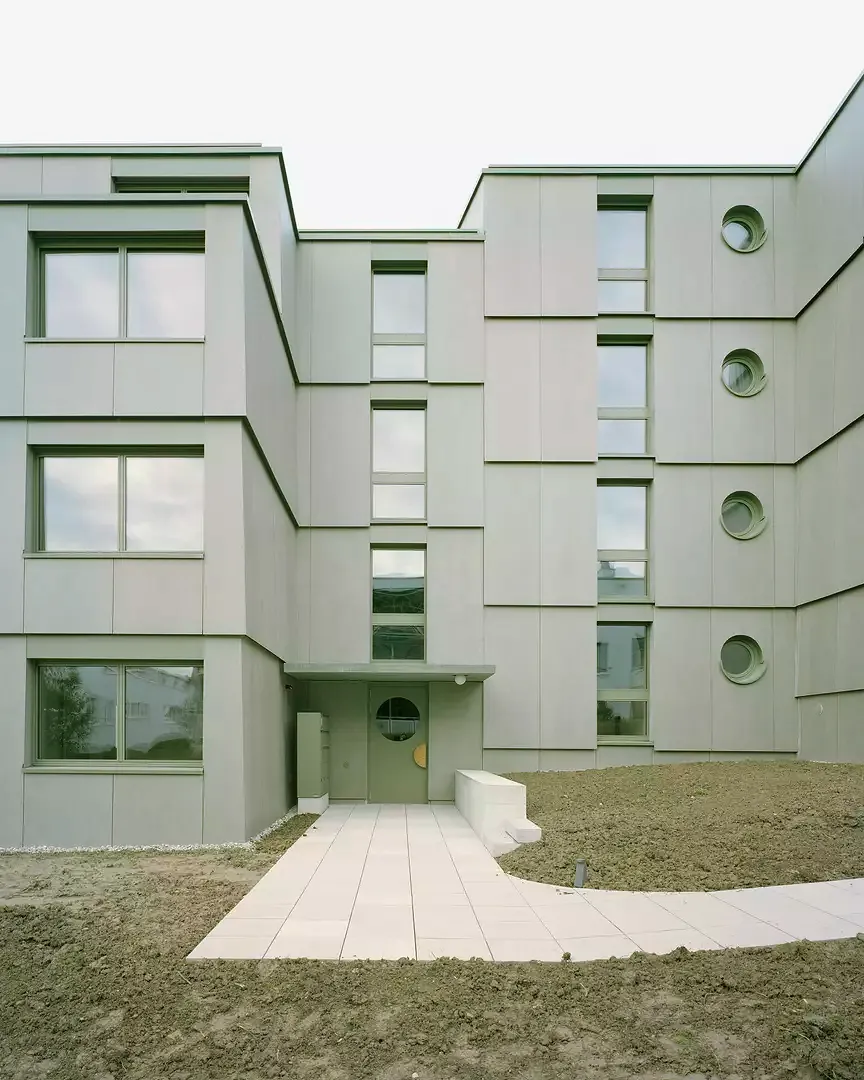 Der Zugang ist volumetrisch zurückversetzt. Hier bildet die Fassade die innere Split-Level Organisation ab.