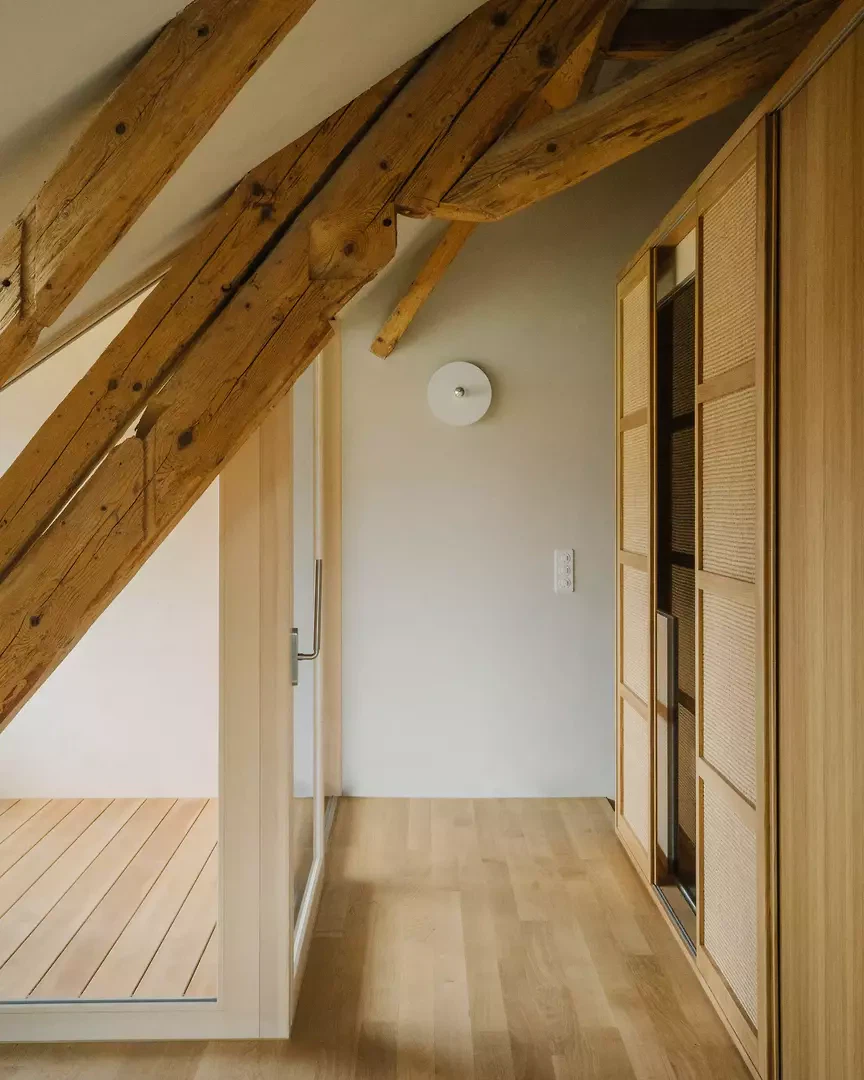 Der hölzerne Einbau im Dachgeschoss des Bauernhauses ist raumbildend und ordnet sich der bestehenden Dachgeometrie unter.