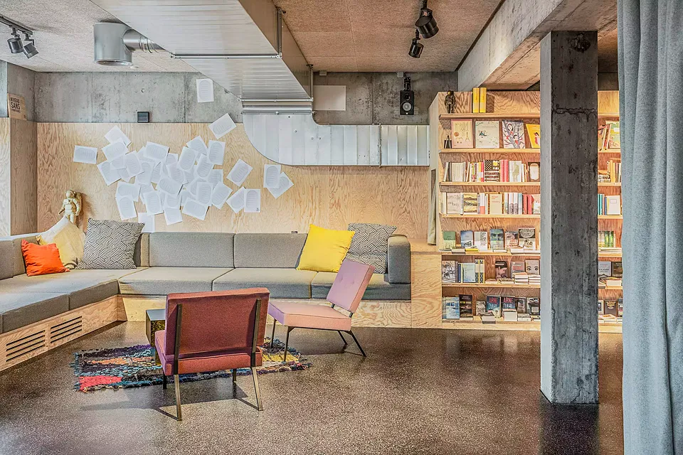 Le café littéraire: la librairie se définit par des matériaux peu coûteux, comme l’asphalte coulé utilisé pour le revêtement de sol et le contreplaqué à  base de pin maritime pour les étagères.