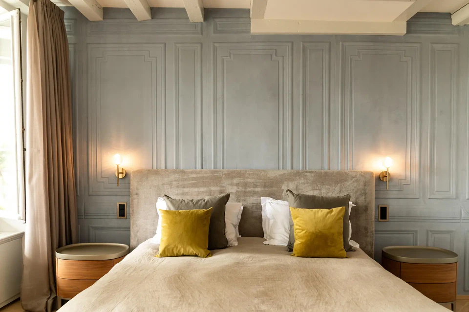 Schlafzimmer mit kassettierter Wandverkleidung in sanfter Farbpalette