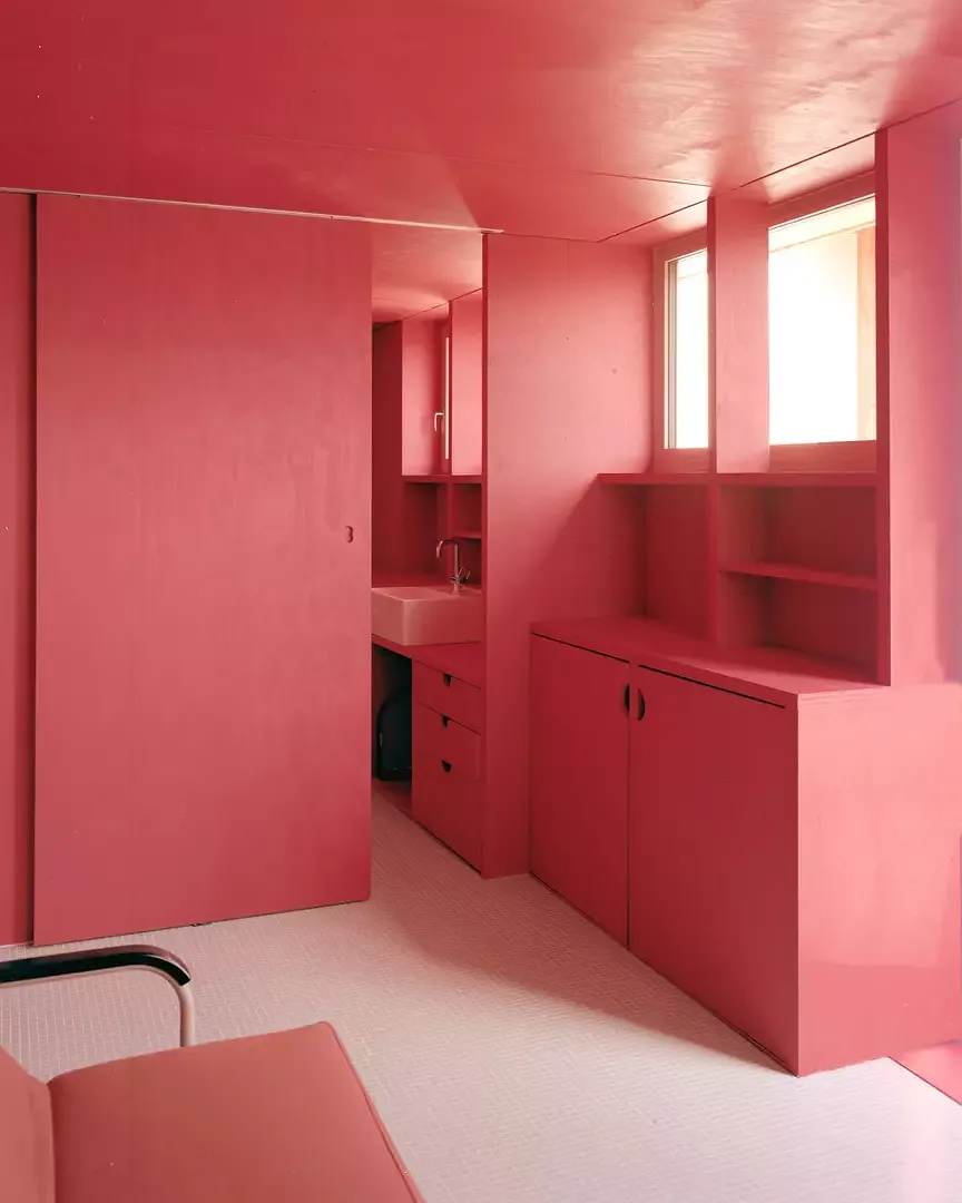 Der Schlafbereich im mittleren Geschoss wird von mattrot lasierten Oberflächen geprägt. Das Elternzimmer und das Gäste- respektive Hauswirtschaftszimmer schliessen an ein dazwischenliegendes Bad an.