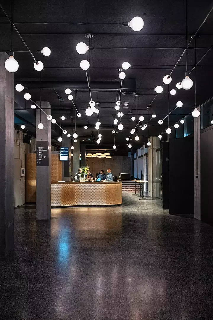 Éclairage: le foyer au rez-de-chaussée avec, à l’arrière,  un club et comptoir de bar.  Le luminaire «Mobile», un  élément spécifique au Kosmos,  illumine toutes les pièces.