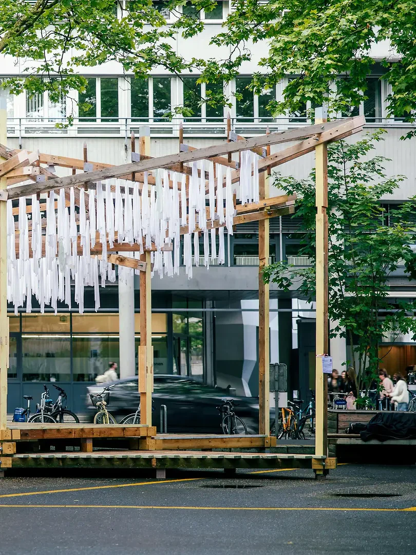 Ein leichtes Dach überspannt die unterschiedlich hohen Holzpodeste und öffnet sich zum Platz hin. Die Struktur «Triangel» zeigt die Spuren der letztjährigen Konstruktion.