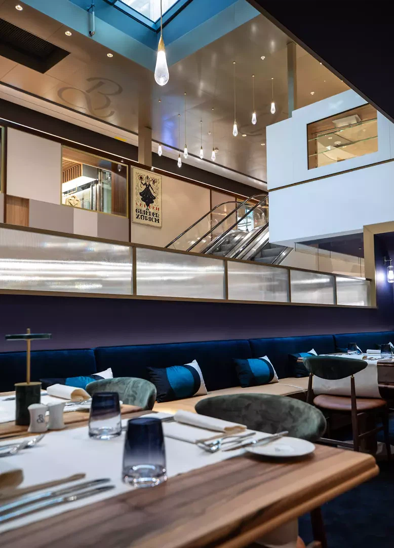 Von einem Atrium belichtet, entstehen Sichtbeziehungen über mehrere Geschosse hinweg – eine Sequenz, die den Raum nicht nur im Inneren, sondern auch zum Strassenraum hin durchlässig erscheinen lässt.