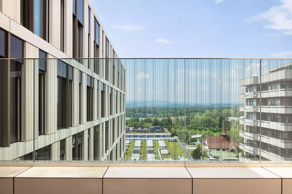 Blick von der Aussenterrasse in Geschoss P nach Nordwesten. Links die Fassade des Anna-Seiler-Hauses, in der Mitte das Dach des INO, rechts daneben die beiden Kapellen und rechts am Bildrand das Bettenhochhaus.