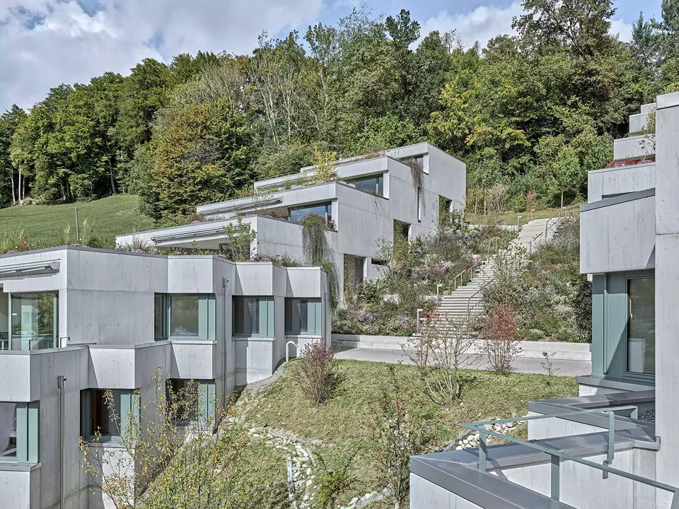 Die Häuserzeilen, die entweder unten oder oben an die Spielstrasse anschliessen, sind so orientiert, dass die dazwischenliegenden Treppen nicht in einer Linie zur jeweils obersten Wohnung führen, sondern auf halber Höhe verspringen.