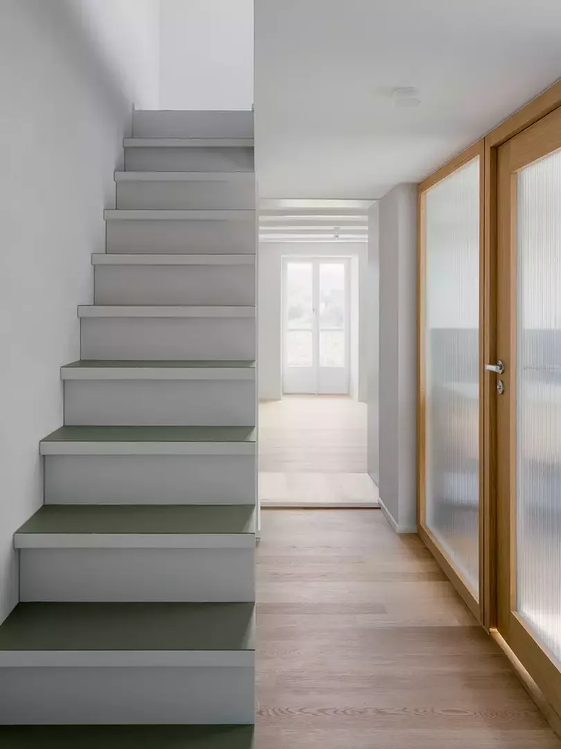 A droite, la salle de bain avec paroi vitrée laissant entrer la lumière dans le couloir