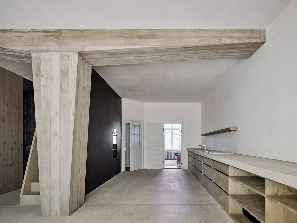La grande cuisine-salle de séjour au rez-de-chaussée  est en béton brut: la colonne avec solive qui ouvre l’espace de la pièce se trouve sur la chape de ciment.