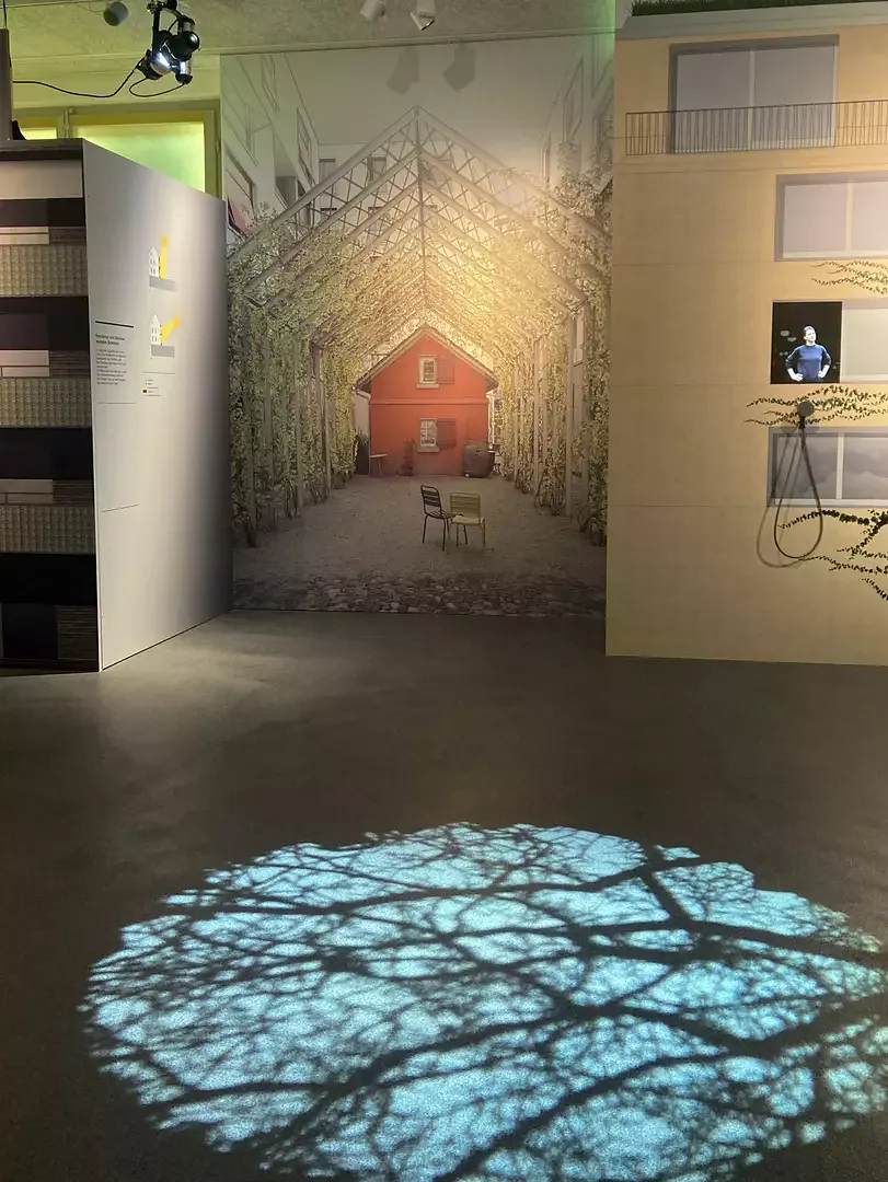 Schatten kann durch unterschiedliche Massnahmen erreicht werden: Ausblick in einen begrünten und beschatteten Innenhof. Im Vordergrund wirft eine Projektion das Blattwerk eines schattenspendenden Baumes auf den Boden.