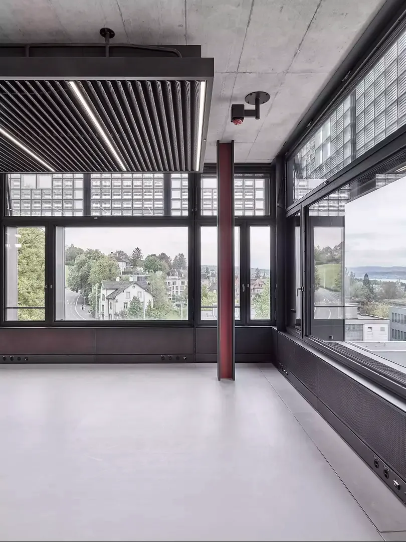 Les poteaux et les tôles sont de couleur rouge bordeaux. Les mêmes matérialisations se retrouvent systématiquement dans les bureaux, les salles de séminaire, les espaces de circulation ainsi que dans le restaurant et les salles de groupe.