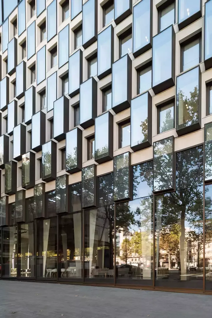 Die Fassaden lassen Blicke vom Boulevard durch das Foyer in den Garten zu. Zwischen die bestehenden Betonrahmen wurden  Fenster in bronzefarbenen Metallboxen eingehangen.
