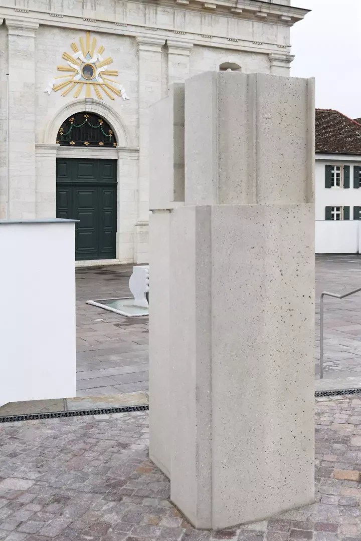 Die Stele aus Kunststein bildet die letzte von insgesamt fünf neuen Leitfiguren auf dem Platz und verweist explizit auf das Herzstück der Anlage, die Gnadenkapelle im Felsen