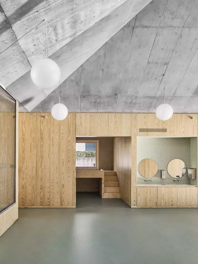 Le plafond en béton apparent du jardin d’enfants démontre une structure similaire à celle des éléments en bois plaqué  qui séparent les jardins d’enfants les uns des autres.