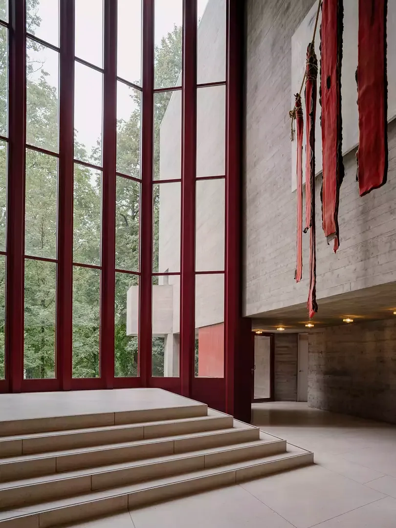 Le choix restreint de matériaux est volontaire: des plaques  de terrazzo et du Redwood ont été combinés avec du similicuir sur les mains courantes et  des éléments métalliques  peints en rouge foncé.