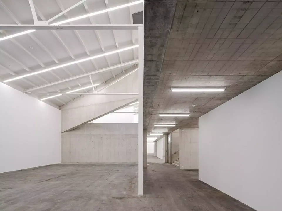 La structure en béton apparent insérée à l’intérieur du manteau existant forme une suite méandreuse d’espaces ouverts.